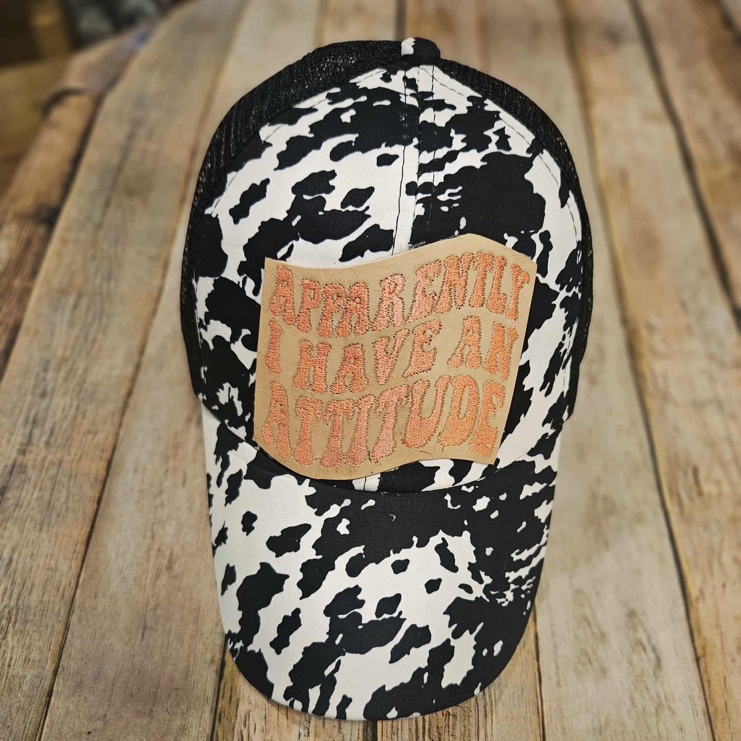 black and white cow print crisscross cap, crisscross ponytail cap, apparently, I have an attitude leather embroidered patch cap, coral embroidered leather patch cap
