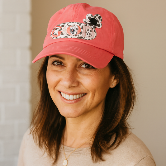 Woman wearing a red cap with a leopard print design against a neutral background