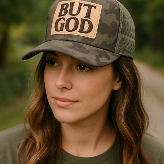Woman wearing a camouflage cap with 'BUT GOD' patch outdoors