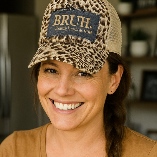 Woman wearing a leopard print cap with 'BRUH' text, smiling indoors.